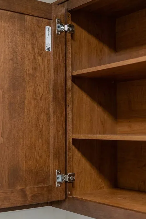 The Encore apartment homes with Open wooden cabinet with two shelves and visible metal hinges on the inside of the door.