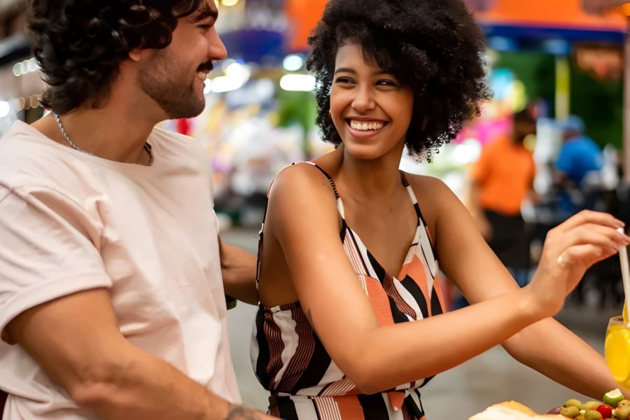 The Encore apartment homes with A smiling couple enjoys food and drinks together at a lively outdoor market.