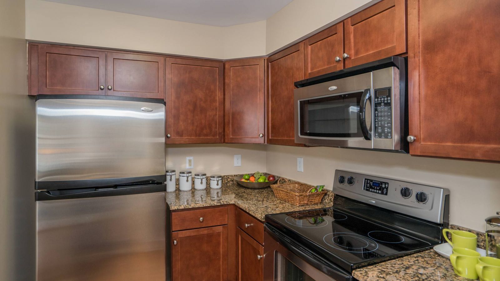 Modern kitchen and living area with white cabinets, stainless steel appliances, and a large island. Cozy seating area with a sofa and rug in the background. Bright and inviting atmosphere.