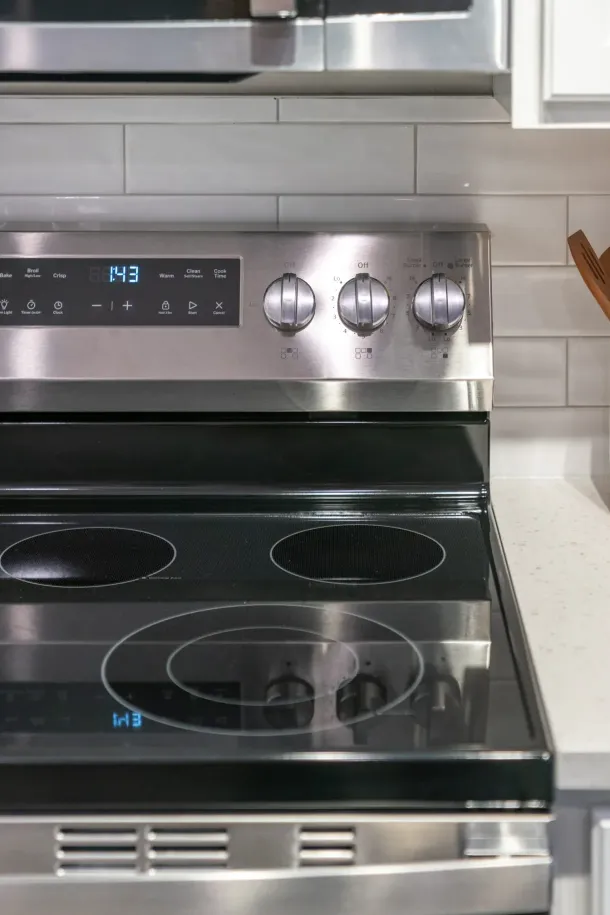 The Encore apartment homes with Stainless steel electric stove with four burners and control knobs, next to a white countertop.