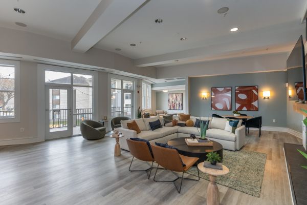 The Encore apartment homes with Modern living room with large windows, sectional sofa, armchairs, and contemporary wall art.