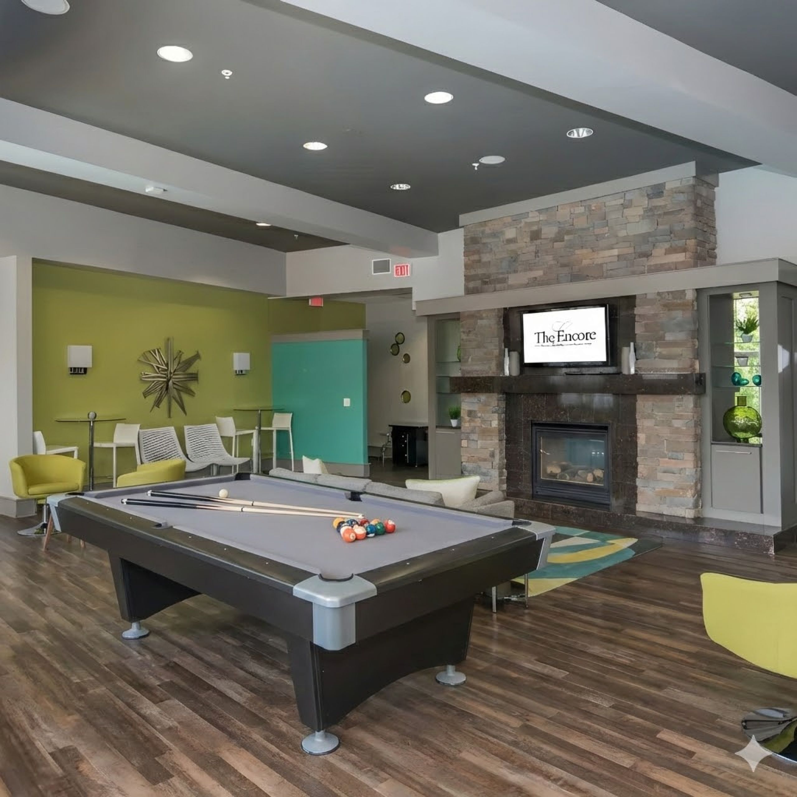 The Encore apartment homes with Modern lounge with a pool table, fireplace, TV, green accent wall, and contemporary seating.