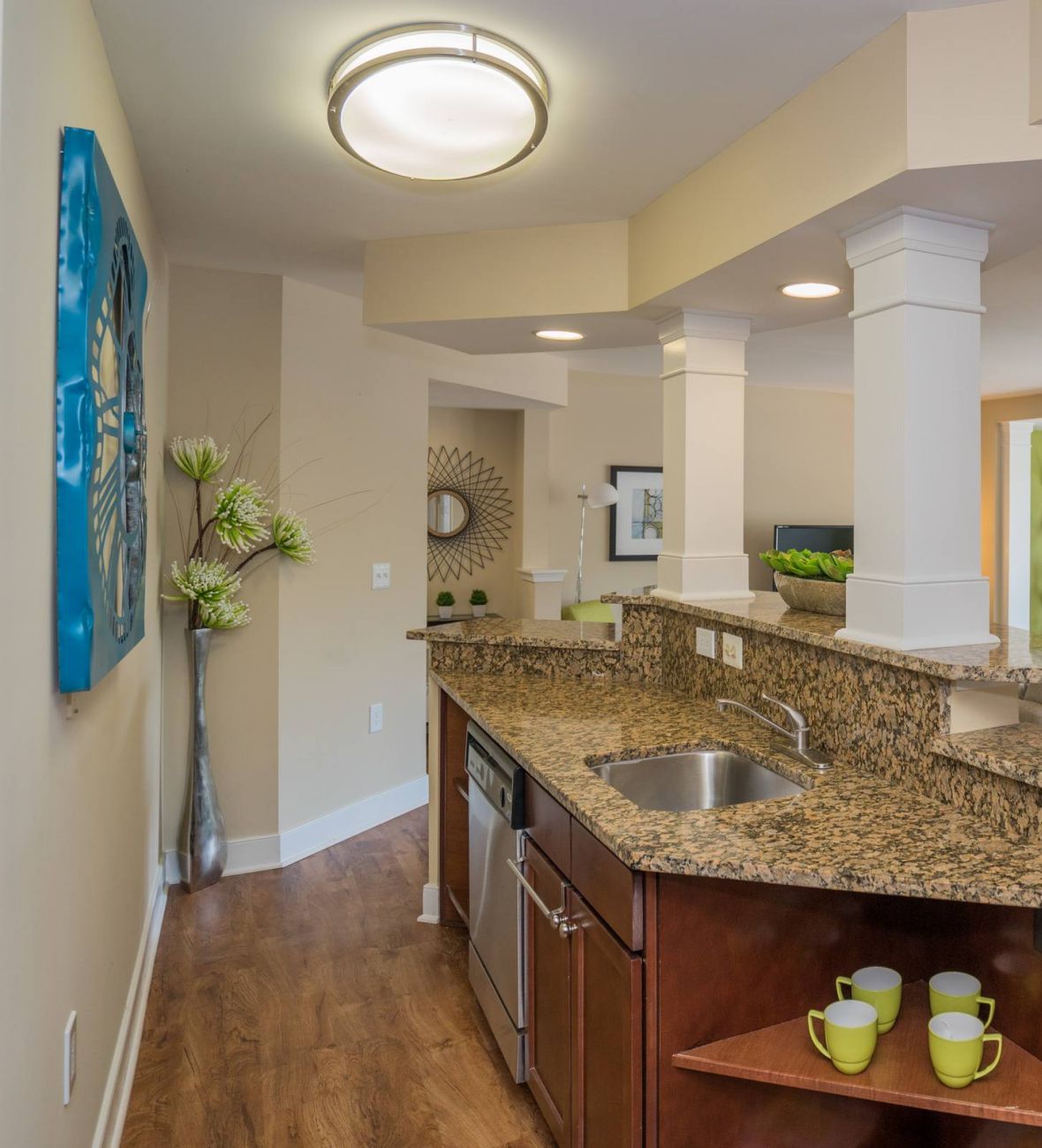 Modern open-plan kitchen and living area with granite countertops, wood floors, and large windows.