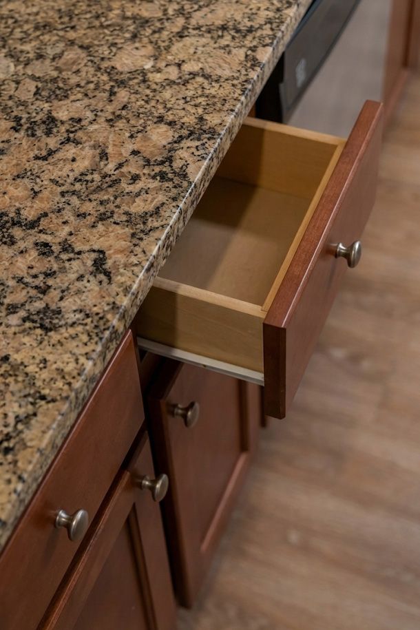The Encore apartment homes with A wooden kitchen drawer is open beneath a granite countertop.